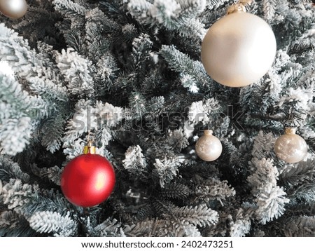 A Christmas tree decorated with white and red Christmas ornaments balls.