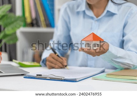 Professional real estate agent signs contract While holding a house. The concept of a home loan contract for housing.
