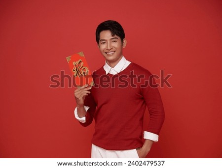 Happy Chinese new year. Asian man holding angpao or red packet monetary gift isolated on red background. Chinese text means great luck great happy.