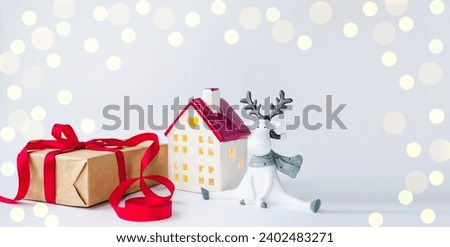 Christmas card on a white background New Year's house, white deer and box with a gift.  Space for copying text.  Christmas and New Year holiday concept.  Foreground.
