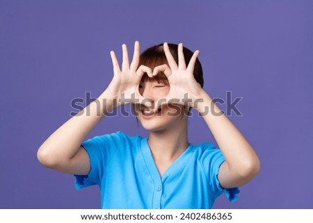 Young beautiful asian woman doing heart shape with hand and fingers smiling looking through sign