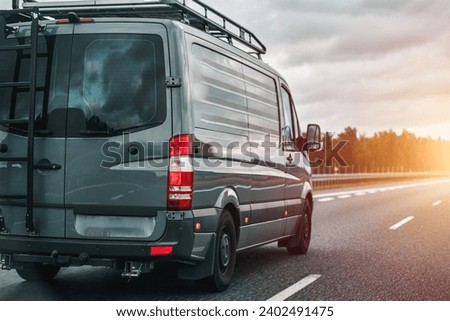 Concept of traveling with a van and enjoying the outdoor adventures. The ultimate van camping in Europe. Offroad modern van for traveling with a ladder on the back and an additional baggage roof rack.