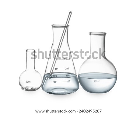 Glass flasks with water and stirring rod isolated on white