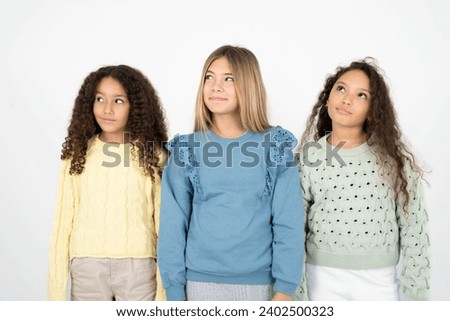 Three young beautiful multiracial kid girls looking aside into empty space thoughtful