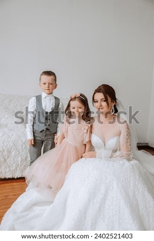 The bride is photographed with small children on the wedding day. A little girl kisses her bride on the cheek.