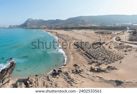 Falasarna sandy beach, Crete island Greece. Aerial drone view of umbrella, seaside sun bed, wavy sea water, summer famous resort vacation. Royalty-Free Stock Photo #2402533561