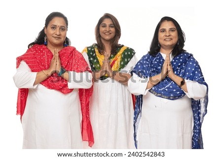 Three happy woman friends hold hands together showing woman unity, woman empowerment and woman health while looking at the camera isolated on white. Wearing white kurta and pajama on festive seasons