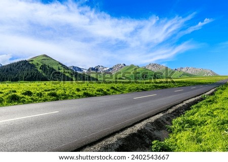 Country road and green meadow with mountain nature landscape under the blue sky Royalty-Free Stock Photo #2402543667