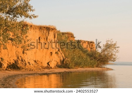 20-meter clay cliffs on banks of Dnieper-Bug freshwater estuary as result of current water erosion and ancient Ozolimna sea reservoir, marine transgression. Landfall, clay slide reeds overgrown as wet Royalty-Free Stock Photo #2402553527