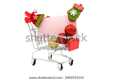 Blank greeting card with wooden decorative clothespins and Christmas tree toys in supermarket grocery shopping cart isolated on white background. 