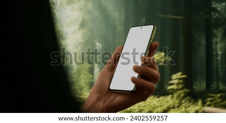 CU Man using his phone outdoors in the forest during hiking or camping trip. Blank screen smartphone mockup, trail, travel, maps, photo application template