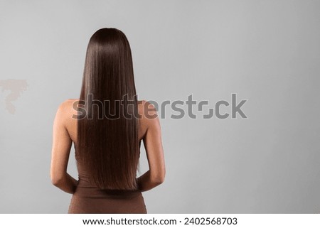 Hair styling. Woman with straight long hair on grey background, back view and space for text Royalty-Free Stock Photo #2402568703