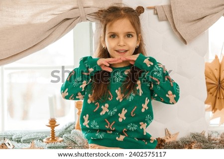 Cute little girl in green sweater with christmas pictures
