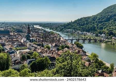 An aerial view of Heidelberg cityscape near a river and green mountains in Germany