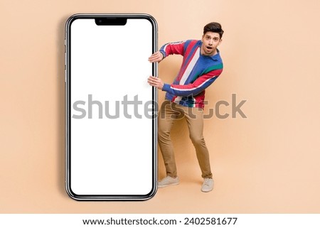 Full length photo of funny surprised man wear striped shirt drag smartphone website page surfing internet isolated on beige color background