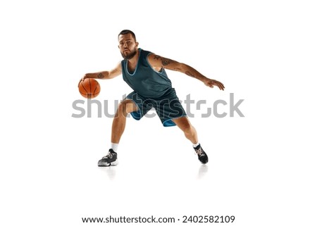 Dynamic portrait of professional basketball player, fit man honing skills with precision dribbling against white background. Concept of sport, hobby, active lifestyle, power and strength. Copy space. Royalty-Free Stock Photo #2402582109