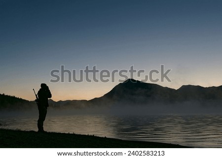 Moose hunter calling at over a lake at dawn