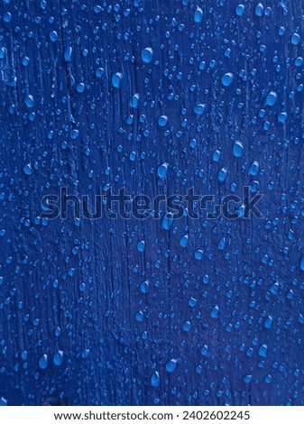Texture of blue painted wood with clear raindrops.