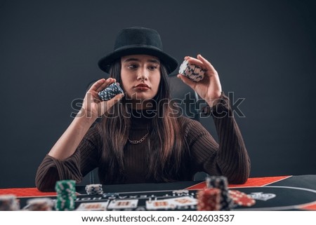 beautiful female playing texas hold'em poker at casino.  Poker or other games concept. Night lifestyle Royalty-Free Stock Photo #2402603537