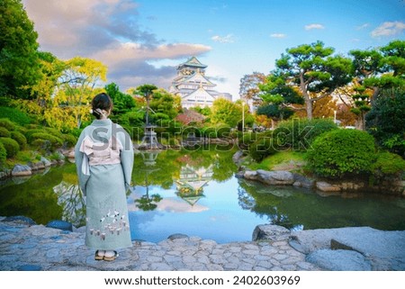 Asain woman wear kimono japanese traditional standing and looking landscape view Osaka Castle at sunset sky in Autumn, Osaka, Japan. Royalty-Free Stock Photo #2402603969