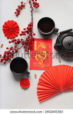 Greeting card with teapot, cups of tea and paper fans on white background. Chinese New Year celebration