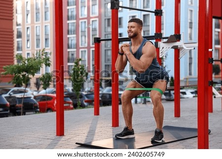 Muscular man doing exercise with elastic resistance band on mat at sports ground