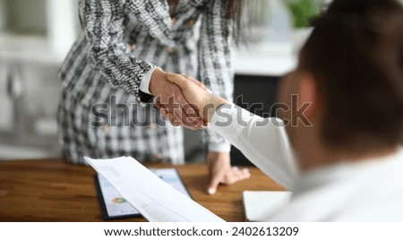 Close-up of businesswoman shaking hands with guest. Young woman in presentable luxury suit in office. Signing contract and make deal. Successful financial company concept Royalty-Free Stock Photo #2402613209