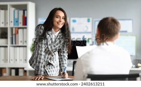 Portrait of pretty smart businesswoman posing on camera and signing contract. Smiling female in presentable costume in company office. Finance and economy concept Royalty-Free Stock Photo #2402613211