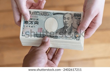 Hand over a wad of Japanese yen Royalty-Free Stock Photo #2402617211