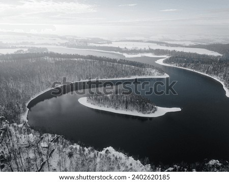 Sec water reservoir with small forested island in the middle. Iron Mountains, Czechia. Aerial view from drone. Black and white photography.