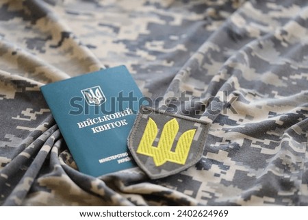 Symbol of Ukrainian army and military ID on the camouflage uniform of a Ukrainian soldier. The concept of war in Ukraine, patriotism and protecting your country from russian occupiers