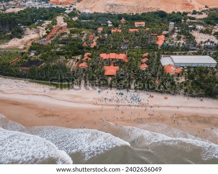 A drone shot of a group of people on a sandy beach with coastal village in Vietnam