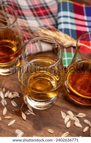 Tasting of different Scotch whiskies strong alcoholic drinks, drum glass of whiskey and colorful Scotch tartan on background close up Royalty-Free Stock Photo #2402636771