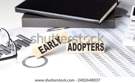 EARLY ADOPTERS - text on wooden block with chart and notebook