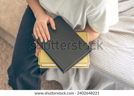 Woman sitting on the sofa and holding books, top view.