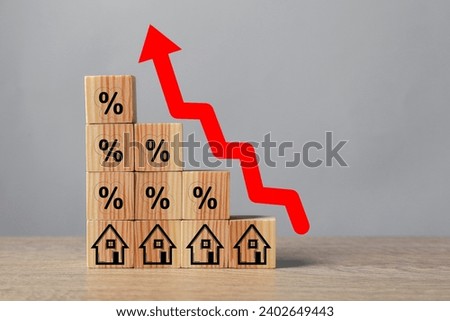 Mortgage rate rising illustrated by upward arrow over cubes with percent signs and house icons on wooden table