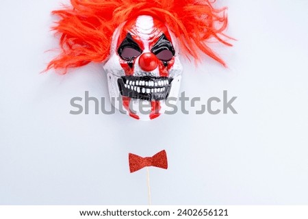 Scary clown mask with a bow on a gray background. Carnival, party and Purim celebration concept. jewish carnival holiday. flat lay, top view. High quality photo