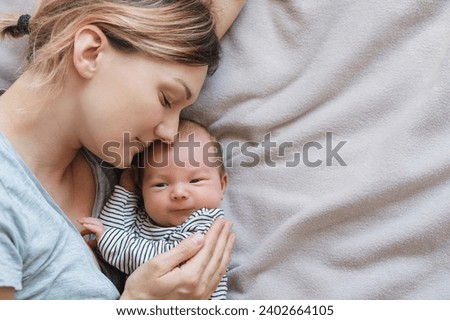 Mother and baby. Loving mom spending time with her little 2 weeks old child at home. Image of bonding mother and baby, healthy physical and mental development of child, happy maternity and family. Royalty-Free Stock Photo #2402664105
