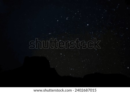 A scenic view of a cloud and starry night sky over the Casa Grande, Chisos Mountains in Big Bend National Park, Texas.