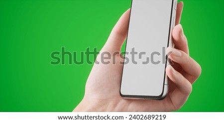 Caucasian woman holding a phone on a plain green screen chroma key background, blank white screen smartphone mockup. Vertical orientation