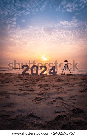 2024 Happy New Year sign at sunset beach with camera and tripod, Photography new year concept background