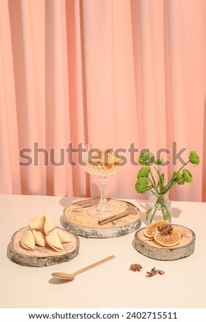 Glass of drink with cookies and flowers and peach colored curtains in the background. Food and drink creative concept.