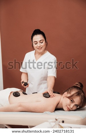 The masseur gives a back massage with stones to the client in the Health room