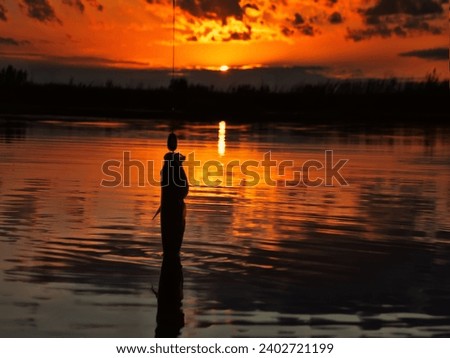 Fishing at sunset. Catching predatory fish on spinning. Sunset colors on the water surface, sunny path from the low sun. Perch caught on yellow spoonbait Royalty-Free Stock Photo #2402721199