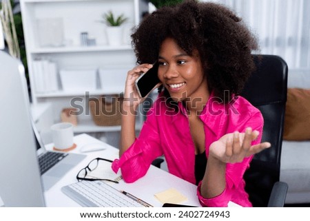 African woman talking with coworker or friend on the phone and looking at the screen with happy face. Achievement for promoting job position in the company with the good news life. Tastemaker. Royalty-Free Stock Photo #2402724943