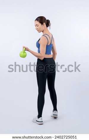 Vigorous energetic woman doing kettlebell weight lifting exercise on isolated background. Young athletic asian woman strength and endurance training session as body workout routine. Royalty-Free Stock Photo #2402725051