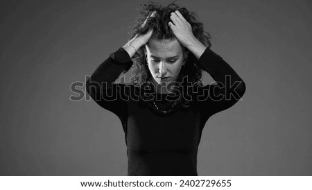 Dramatic desperate scene of woman pulling hair in black and white. Person feeling dread and preoccupation