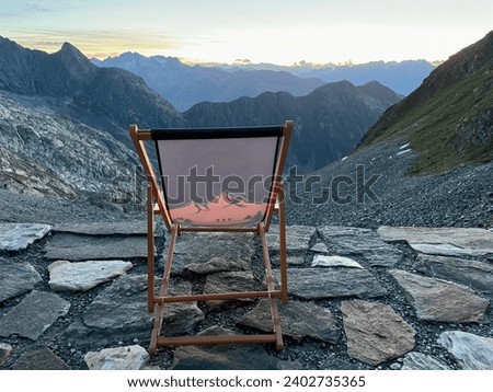 Red deckchair on terrace of mountain hut at sunset, breathtaking view of Swiss Alps. High quality photo