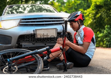 Car Crashes into a cyclist falls and injures his knee, Cyclist in Need of Urgent Aid, Unexpected Roadside Encounter and Immediate Assistance for Outdoor Mishaps Car Crash. Royalty-Free Stock Photo #2402738443