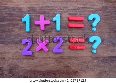 Arithmetic examples from plastic numbers and multiplication and addition signs on a wooden surface. Learning to count, education